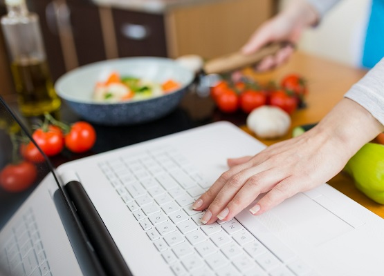 uśmiechnięta dziewczyna sprawdzająca przepis na laptopie